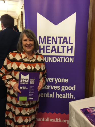 Fiona Bruce MP in front of a purple mental health awareness banner